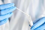 A picture of a scientist holding a swab and a saliva sample