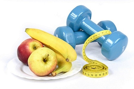 Apples and bananas on a plate with blue dumbbells and a yellow tape measure