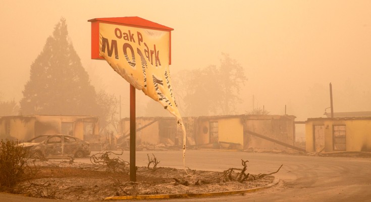 The melted sign of a motel stands in front of a series of burnt out buildings