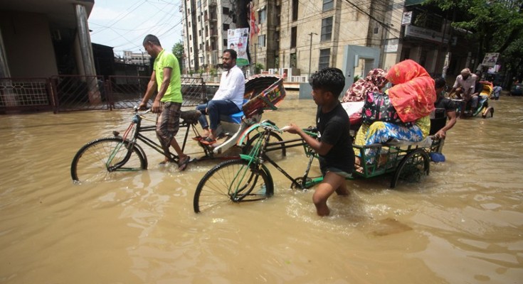 Rickshaw pullers transport customers along a knee-high flooded street 