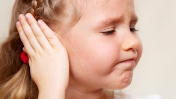 Kleines Mädchen hält sich ein Ohr zu