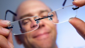 Mann hält Brille in den Händen