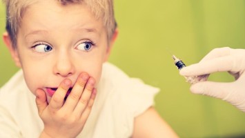 Junge blickt skeptisch auf Spritze