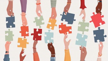 Hände halten bunte Puzzleteile nebeneinander. 