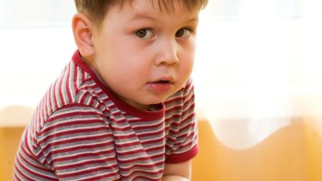 Kleiner Junge hält sich den Bauch