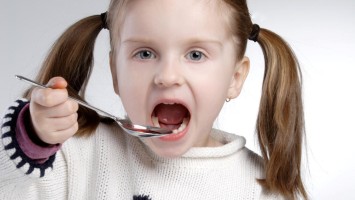 Kind schluckt flüssige Medizin