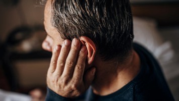 Älterer Mann fasst sich ans Ohr