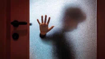 Junge hinter Glastür