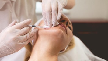 Einer Person wird eine Spritze am Kinn verabreicht