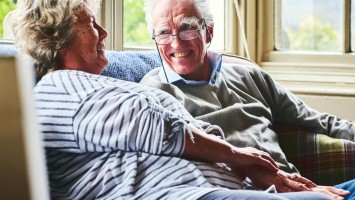 Älteres Paar sitzt lachend beisammen