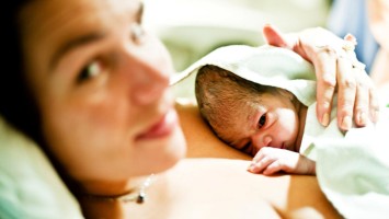 Neugeborenes liegt auf der Brust der Mutter