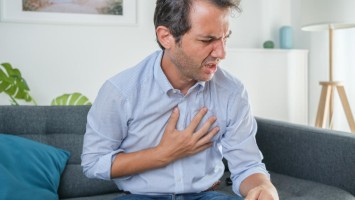 Mann greift sich mit der Hand an die Brust