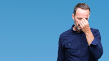 Ein Mann hält sich die Hand an die Nase
