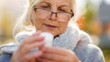 Frau betrachtet kritisch eine Pillendose