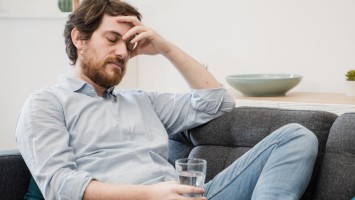 Erschöpfter Mann hält ein Glas Wasser
