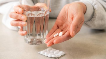 Hände halten Tabletten und Glas mit Wasser