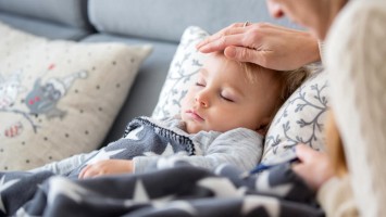 Frau hält Hand über den Kopf eines schlafenden Jungen
