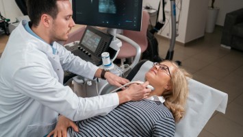 Arzt führt Ultraschall am Hals einer Frau durch