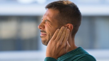 Ein Mann hält sich schmerzverzerrt die Hand ans Ohr