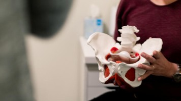 Frau hält Modell eines weiblichen Beckens