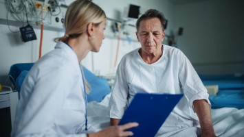 Ärztin spricht mit Patient am Krankenbett