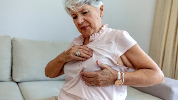Ältere Frau fasst sich an die Brust