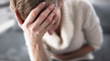Frau mit Kopf- und Bauchschmerzen