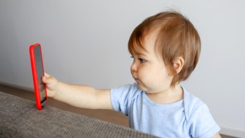 Kleinkind starrt auf Bildschirm eines Smartphones