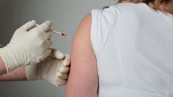 Person injiziert Medikament in den Arm einer Patientin