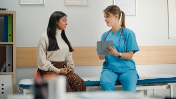 Medizinisches Personal redet mit einer Person im Untersuchungsraum