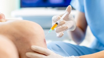 Ärztin gibt Patienten Gelenkspritze