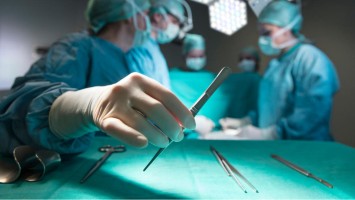 Eine Pinzette wird vom Tisch genommen während einer OP