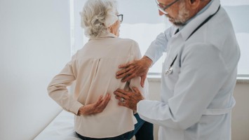 Arzt klärt Rückenschmerz bei älterer Patientin ab