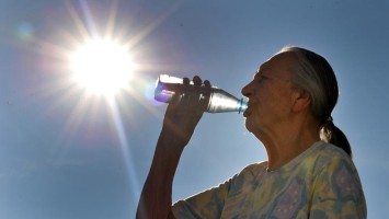 Ältere Frau trinkt aus einer Wasserflasche
