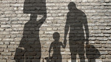 Schatten einer Frau, eines Kindes und eines Mannes auf einer Mauer