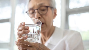Seniorin führt Wasserglas zum Mund
