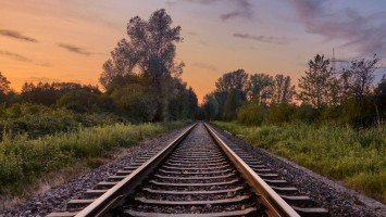Schienen, die im Grünen im Abendlicht in die Ferne führen