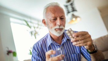 Älterer Mann schaut kritisch auf Tabletten