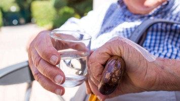Senior mit Wasserglas bei Hitze