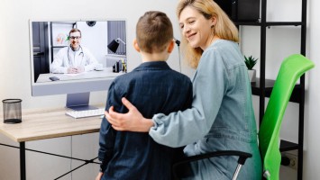 Mutter und ihr Kind sitzen zusammen in Videosprechstunde