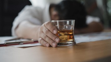 Schlafender Mann mit alkoholischem Getränk in der Hand