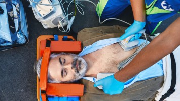 Rettungssanitäter mit Defibrillator bei der Wiederbelebung eines Mannes
