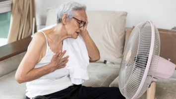 Seniorin vor Ventilator sitzend leidet unter Hitze