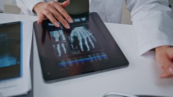 Ärztin analysiert Röntgenbild einer Hand auf dem Tablet