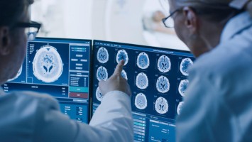 Arzt und Ärztin unkenntlich diskutieren Gehirn-Scans