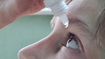 Kind erhält Augentropfen