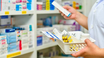 Apothekerin holt Arzneimittel aus Regal