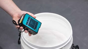 Menschliche Hand hält Messgerät über weißem Eimer 