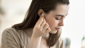 Eine Frau setzt sich Earbuds auf