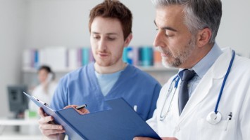 Älterer Arzt mit Arzthelfer schauen über Patientenakte